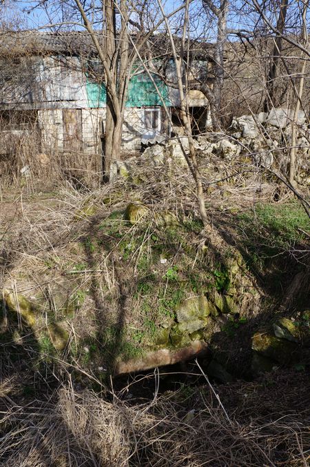 яма с трубой на фоне старого брошенного дома